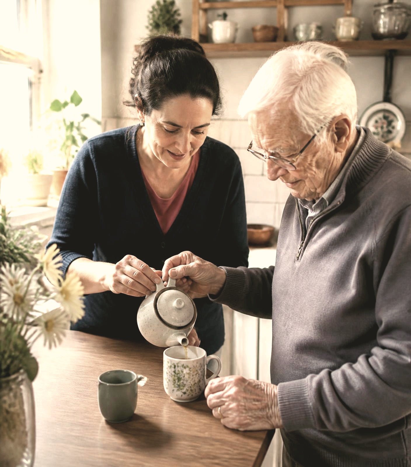 A caregiver and an older adult sharing tea together in a warm kitchen